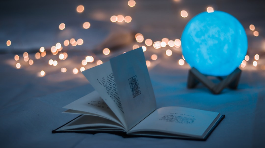 Open book laying on a table, sitting in front of a blue globe on a stand